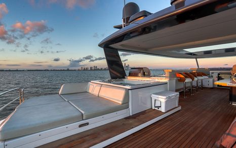 Motor Yacht Saint flybridge sunpad area with seating and panoramic ocean views at sunset