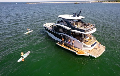Aerial view of the Galeon 620 Fly with fold-down beach club terraces and hydraulic bathing platform deployed at anchor.
