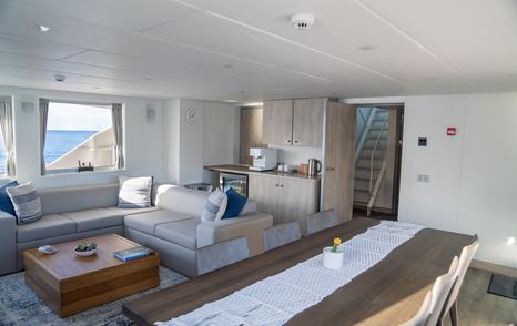 The main salon aboard support vessel SHADOW is functional, complete with a dining table and sofas for crew or guests