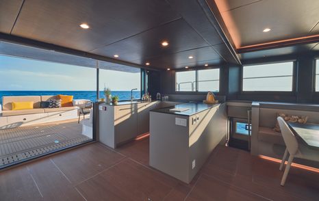 The galley aboard the  Silent 62 3-Deck Open features grey U-shaped countertops and easy access to the aft deck