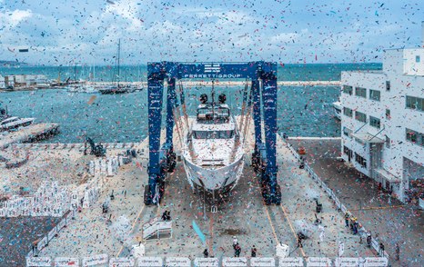 Custom Line 140 in crane during launch ceremony, showered with confetti and surrounded by Ferretti facility in Ancona.