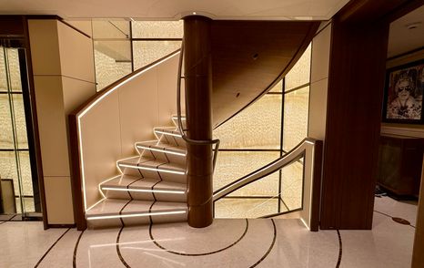 Central staircase and elevator lobby on the Amels 242 Casino Royale featuring marble walls and curved stair design.