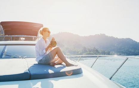 young female drinking on bow of motor cruising yacht