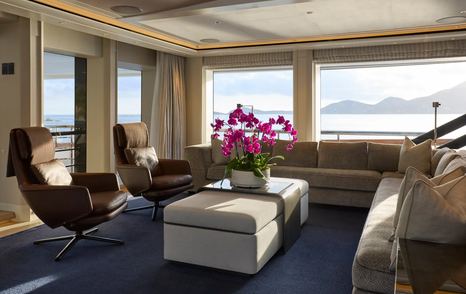 Feadship Superyacht Vanish skylounge with blue carpet, grey L-shaped sofa and beige coffee table 