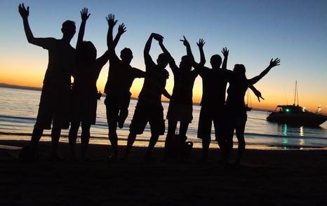 silhouette of friends in front of boat on anchor