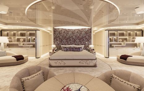 Overview of the master cabin onboard superyacht Lady Jorgia. Central berth with plush seating either side and display cases in the background.