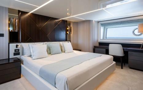 Motor Yacht Triple Eight master cabin with double bed, desk area and modern wood finishes