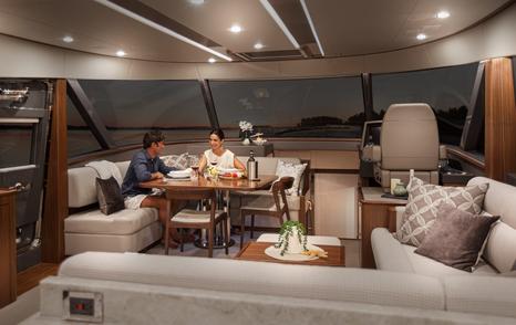 Riviera Belize 66 Daybridge boat main saloon with couple eating at dining table 