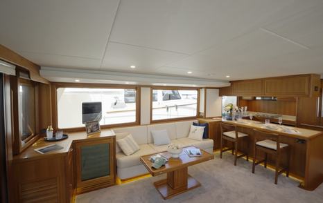 Fleming 85 open-plan saloon and galley with large windows and teak joinery