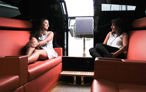 Two women in interior of limousine tender talking on comfortable seating