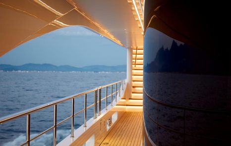 View from side of Aft lounge area of Benetti Diamond 145 INK superyacht with illuminated steps in background 