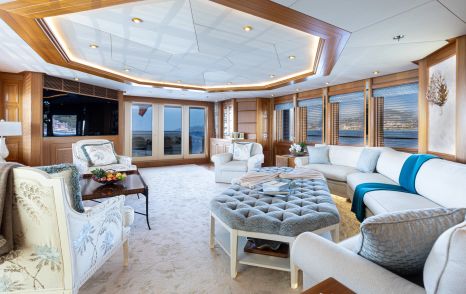 Superyacht Vibrance main saloon with curved white seating and plush grey coffee table 