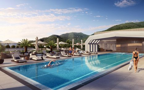 Swimming pool facility at hotel SIRO. One visitor swimming with another lady walking with a towel. Sunloungers on far side.