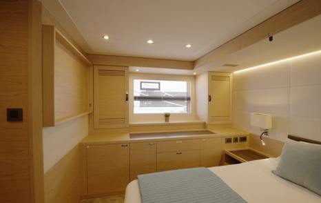 Beneteau Grand Trawler 63 owner's cabin with hull windows, bedside storage and natural oak joinery