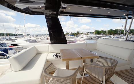 Beneteau Grand Trawler 63 flybridge lounge with U-shaped seating, dining table and panoramic views