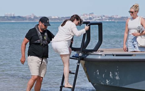 Guest stepping ashore from the bow of the Evene Origin 71 using the beach ladder
