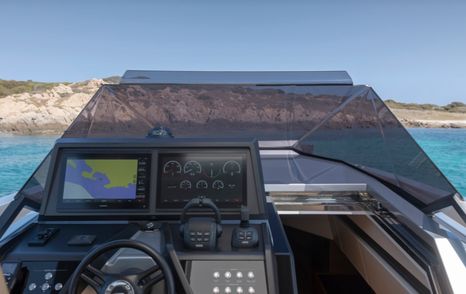 Overlooking the control panel and steering setup onboard Wally 48 Wallytender, surrounded by sea and cliff face