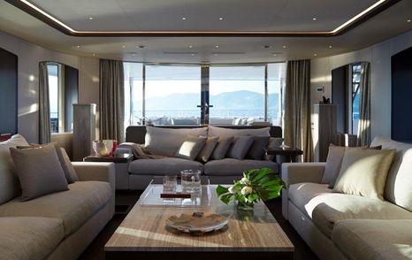 Sofas and table on Benetti Diamond 145 INK superyacht with glass doors in background and flowers and fruit on table