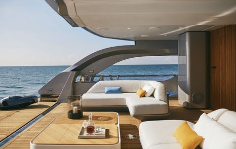 Side view of Azimut Grande Trideck Beach Club, white sofas and scatter cushions with coffee table overlooking aft views.