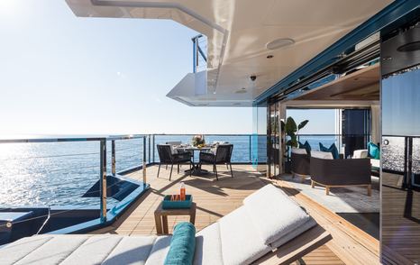 Expedition yacht King Benji aft deck with glass sliding doors and sunpads