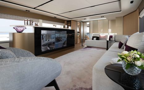 Plush lounge area onboard the Majesty 111, large flatscreen TV surrounded by white upholstered sofas and armchairs.