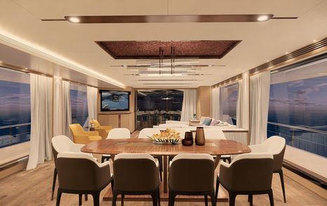 wooden dining table surrounded by brown and white chairs in the window-lined main salon of FD92 yacht