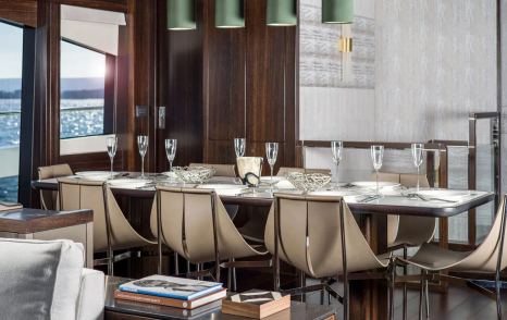 Close up image of Sunseeker 88 Yacht dining area, long table with eight chairs, adorned with cream accessories.