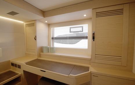 Beneteau Grand Trawler 63 owner's cabin workspace with dressing table, wardrobe and large hull window