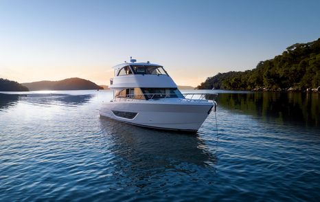 Maritimo M50 enclosed flybridge yacht at anchor viewed from aft quarter in calm water