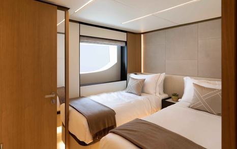 Overview of a twin cabin onboard the Majesty 111, two single beds on either side of a cabin with a door leading to an ensuite.