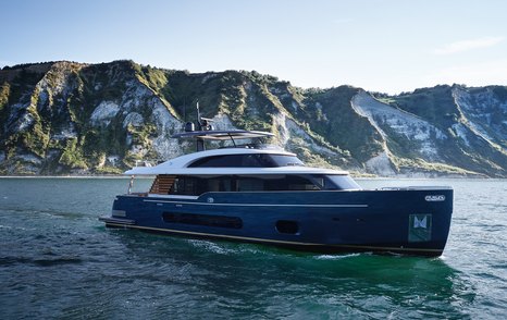 Magellano 25 Metri at anchor, surrounded by sea with cliff face in background