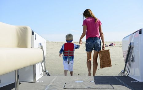 Mother and young son stepping off of beachlander tender onto beach