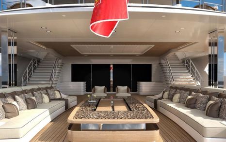 Sundeck on LANA superyacht. Large comfortable sofas and large rectangular table in the center with stairs going up behind.