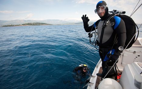 Man diving off yacht with wet suit and gear on 