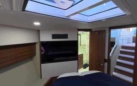 Maritimo M50 forward guest cabin showing skylights, TV and access to lower deck stairs