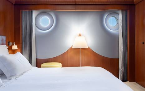 Wedge Too yacht guest cabin with porthole windows and wood paneling