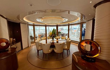 Private dining area on the owner’s deck of the Amels 242 Casino Royale with circular table and panoramic glazing aft.