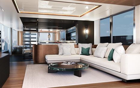 Main salon onboard Sunseeker Ocean 156. White L shaped seating around a coffee table and large windows adjacent. Stairs visible in background.