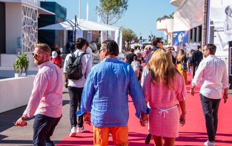 Visitors walking along a red carpet between exhibitors at the Cannes Yachting Festival