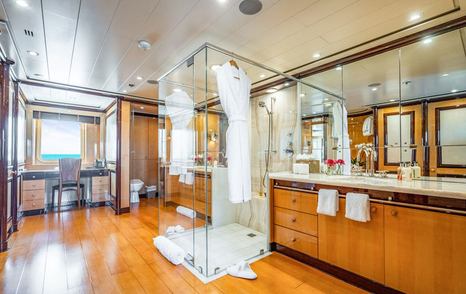 Motor yacht Nita K II's ensuite with glass shower, wooden flooring, double vanity, large mirrors, and natural light from windows