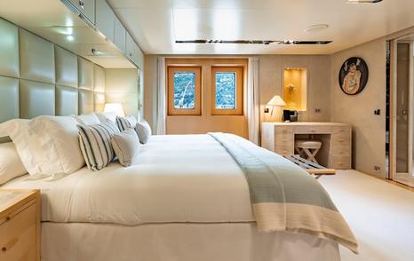 Guest cabin on motor yacht Loon with large bed, teal details and a vanity