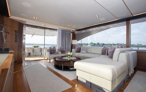 Motor yacht Lady J main saloon white L-shaped sofa and glass sliding doors 