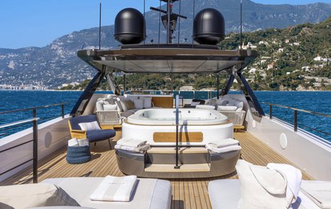 Overview of the sun deck onboard the Custom Line 140. Central Jacuzzi with sun loungers in foreground.