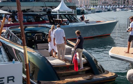 Group of three people standing on a tender among superyachts on display at the Cannes Yachting Festival