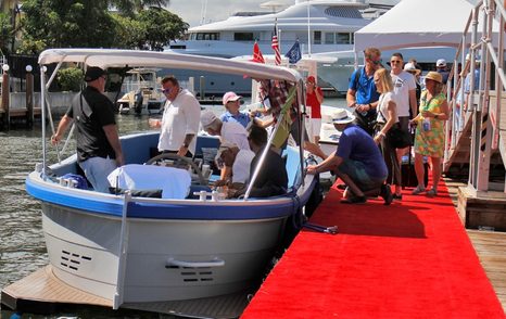 Tenders line up along a dock adorned with a red carpet, with visitors being aided on and off the boats