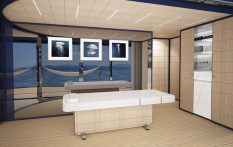 White massage bed, with photos of jellyfish on glass wall behind it, with sea visible through glass wall.