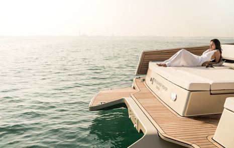 Lady in white dress on white sunlounger at back of Sunreef Yachts 40 Open Power tender, with sun setting in the background and calm sea in the foreground