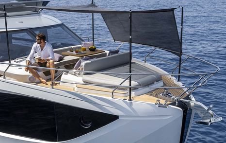 Next-Gen Absolute 52 FLY motor yacht foredeck with grey canopy and man on sunbed 