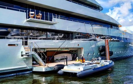 Tender boat on water next to open garage of superyacht