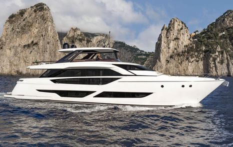 Ferretti Yachts 860 underway, passing cliff face in background.